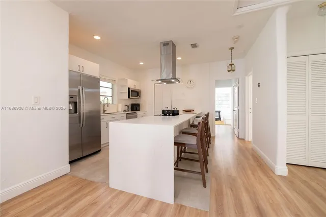 a kitchen with stainless steel appliances kitchen island hardwood floor and a sink