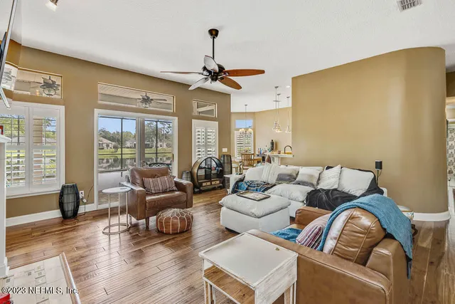 a living room with furniture ceiling fan and a large window