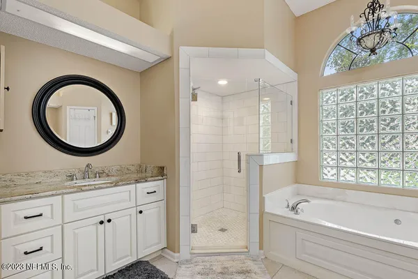a bathroom with a granite countertop sink a mirror a bathtub and shower