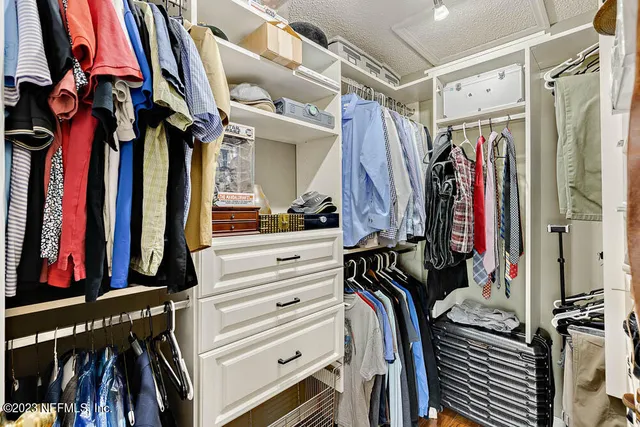 a view of walk in closet with clothes and shoes