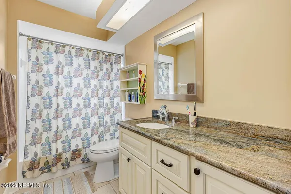 a bathroom with a granite countertop sink a toilet and a mirror