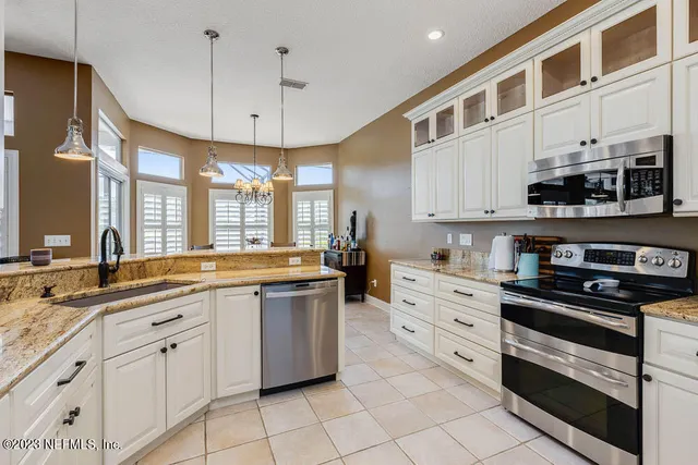 a large white kitchen with stainless steel appliances granite countertop a stove a sink and a microwave