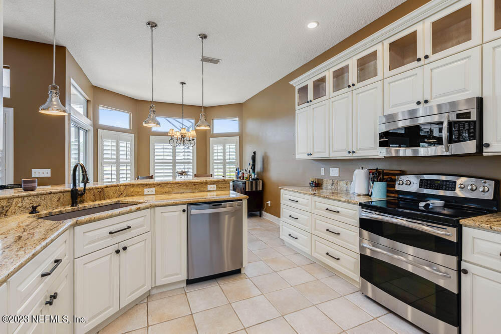 332 Maplewood Drive St. Johns, FL 32259 - Photo 10 of 35 a large white kitchen with stainless steel appliances granite countertop a stove a sink and a microwave