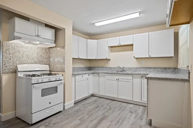 a kitchen with granite countertop cabinets stainless steel appliances and wooden floor
