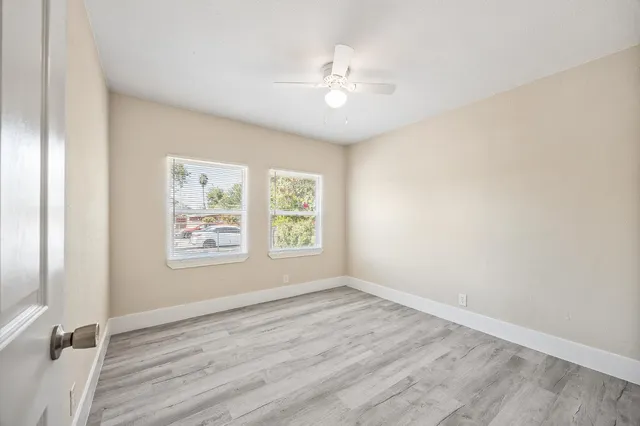 a view of an empty room with a window and wooden floor