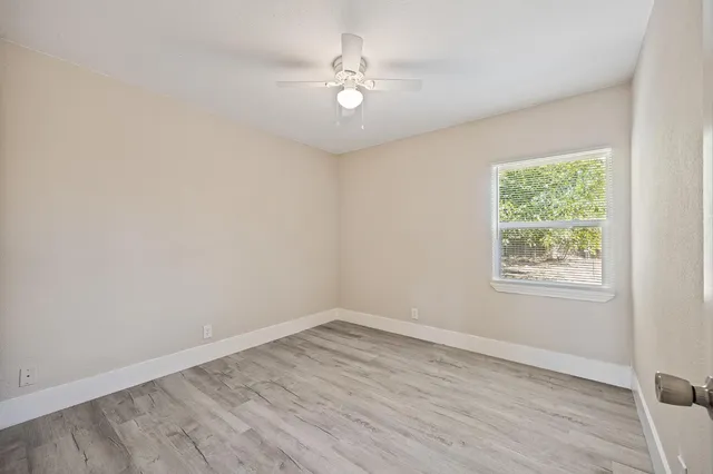 an empty room with a window and a fan
