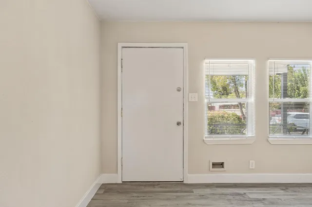 a view of an empty room with wooden floor and a window