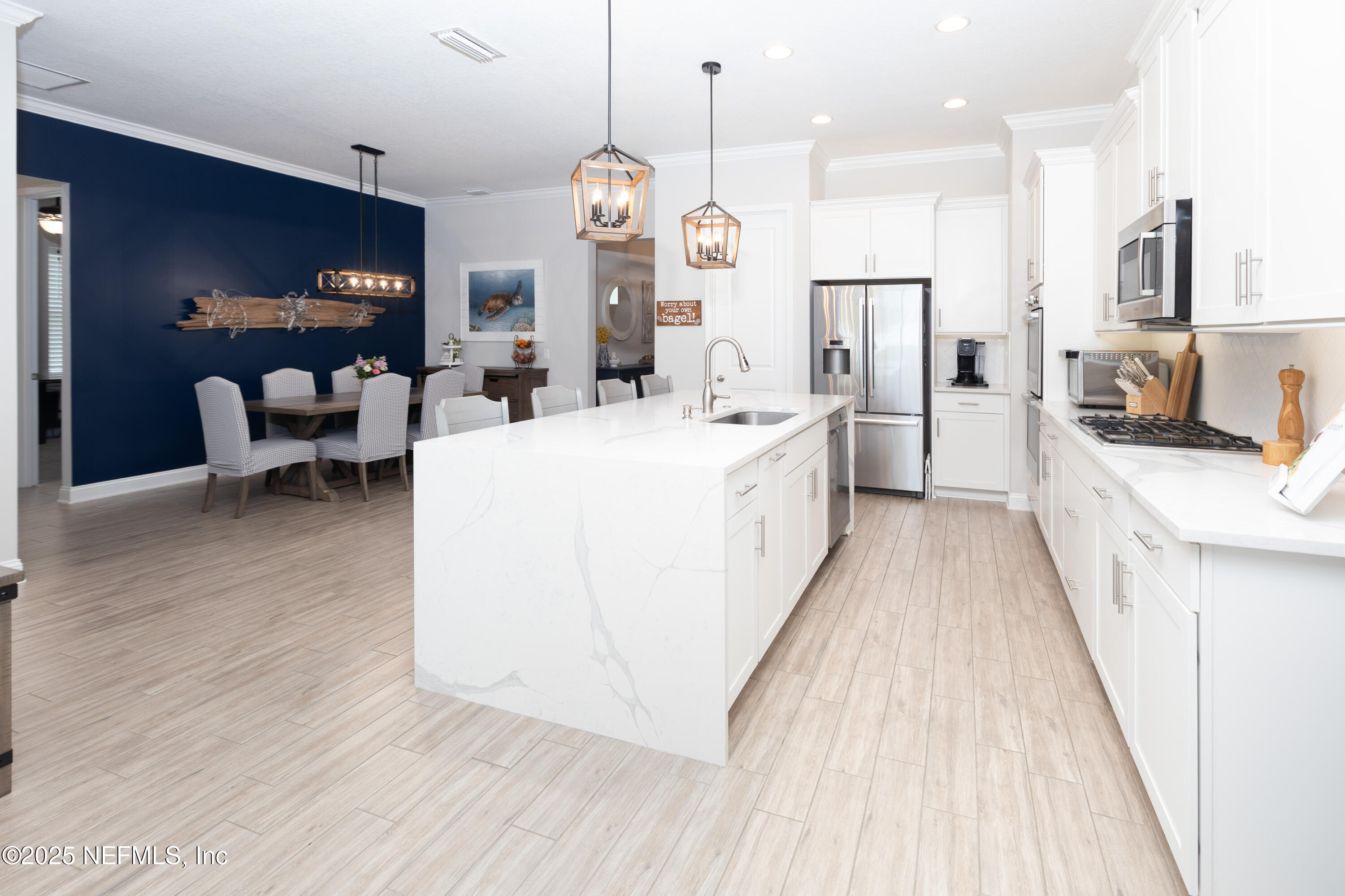 a large kitchen with stainless steel appliances kitchen island granite countertop a stove a sink a refrigerator and a dining table with wooden floor