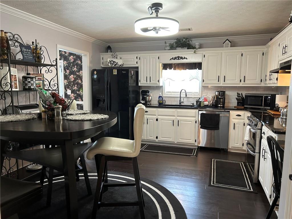 4197 Wyndham Ridge Court Northeast Buford, GA 30519 - Photo 7 of 49 a kitchen with stainless steel appliances granite countertop a sink dishwasher a stove a refrigerator a dining table and chairs with wooden floor
