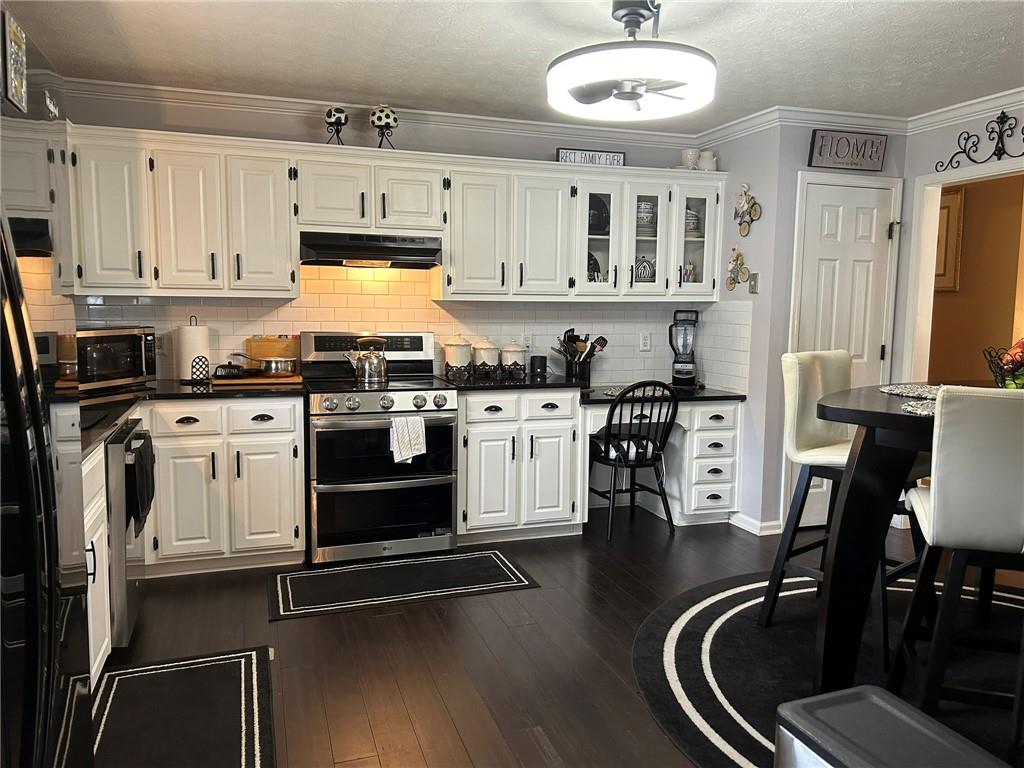 4197 Wyndham Ridge Court Northeast Buford, GA 30519 - Photo 9 of 49 a kitchen with stainless steel appliances a stove a refrigerator cabinets and a dining table