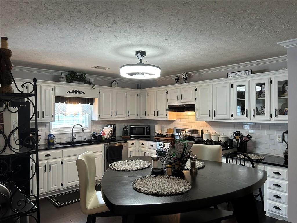 4197 Wyndham Ridge Court Northeast Buford, GA 30519 - Photo 10 of 49 a kitchen with granite countertop a stove a sink a dining table and chairs