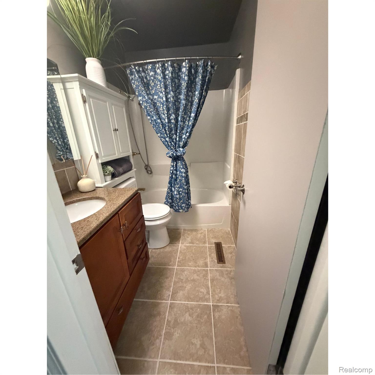 1451 Wilshire Road Haslett, MI 48840 - Photo 21 of 42 Bathroom featuring a built-in vanity with a granite-style countertop and integrated sink, tiled flooring, and a white bathtub with a shower surround