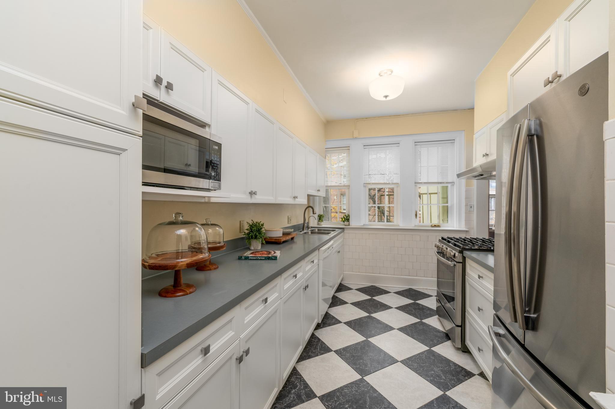 102 West 39th Street, Unit 2B Baltimore, MD 21210 - Photo 12 of 30 a kitchen with a sink a refrigerator and cabinets