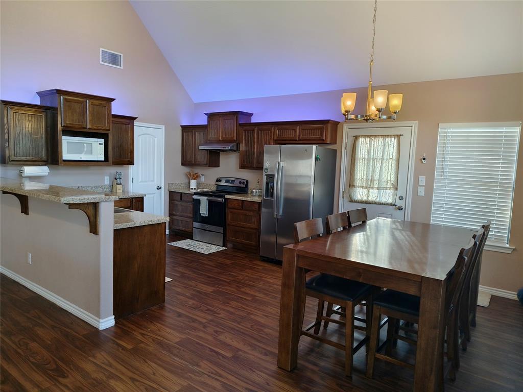 100 East Bluebonnet Drive Cresson, TX 76035 - Photo 18 of 25 Kitchen featuring a peninsula, stainless steel appliances, high vaulted ceiling, a breakfast bar area, and dark wood-style flooring