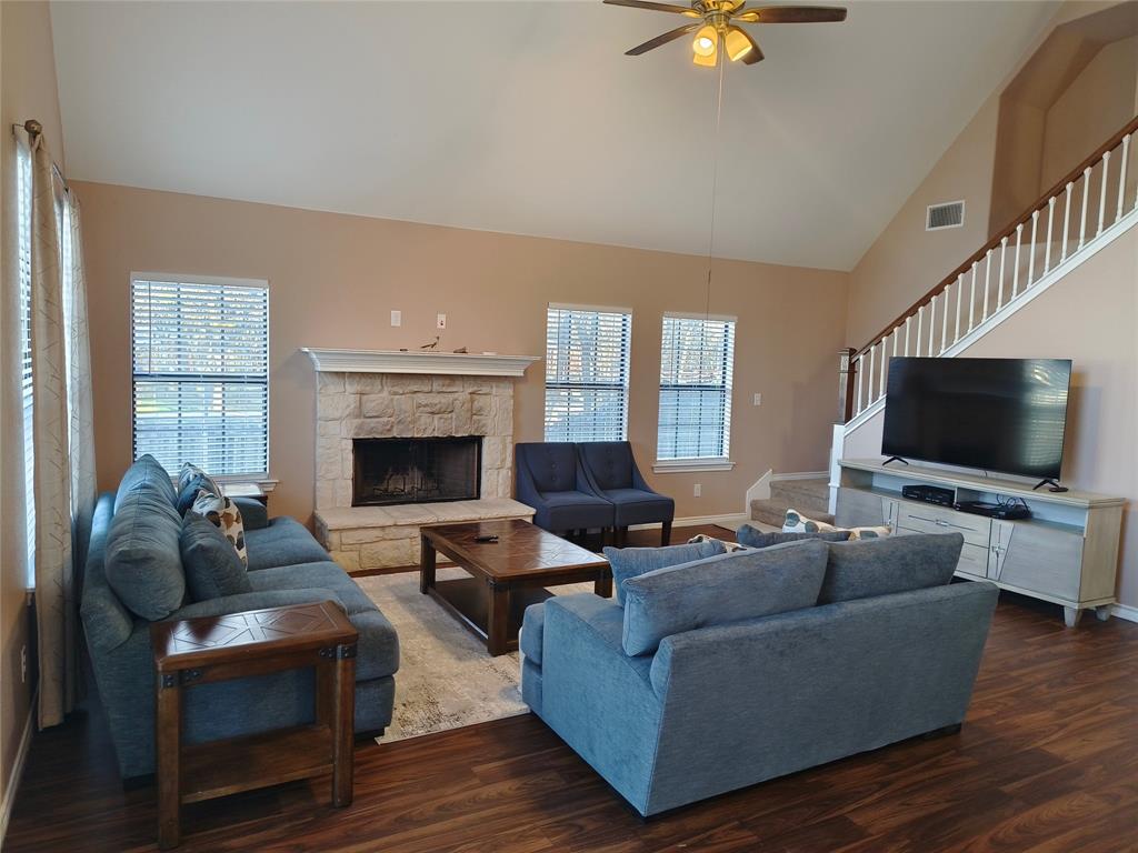 100 East Bluebonnet Drive Cresson, TX 76035 - Photo 10 of 25 Living room with stairway, dark wood-style flooring, high vaulted ceiling, a stone fireplace, and a ceiling fan