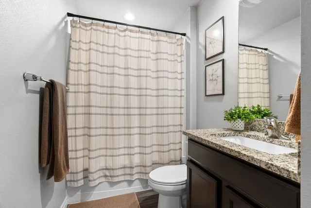 a bathroom with a granite countertop sink toilet and shower