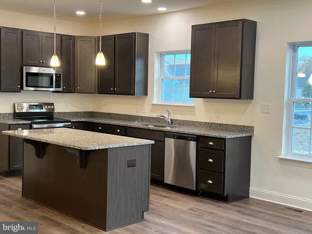 a kitchen with a sink and a stove top oven with wooden floor