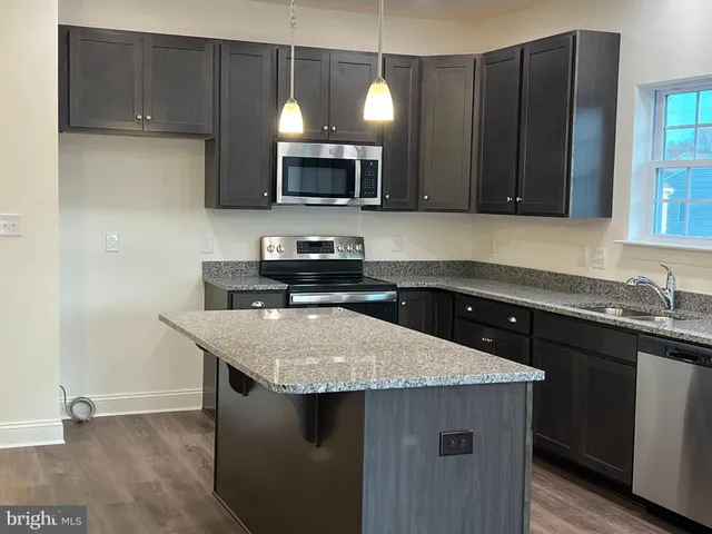 a kitchen with stainless steel appliances granite countertop a sink a microwave a stove and a microwave