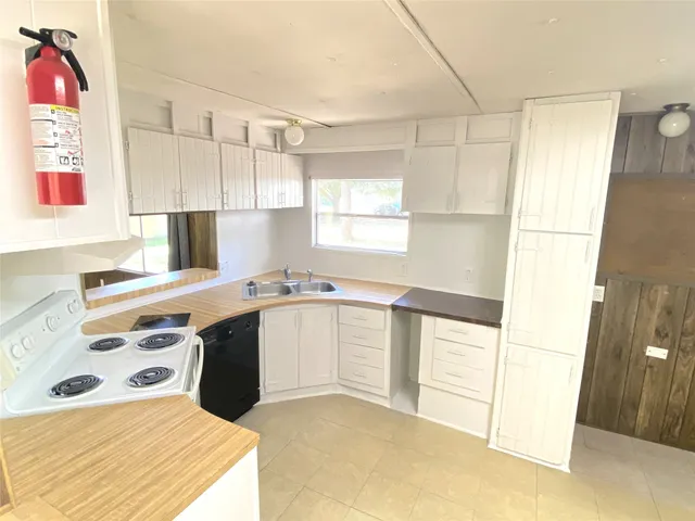 a kitchen with a stove a sink and white cabinets