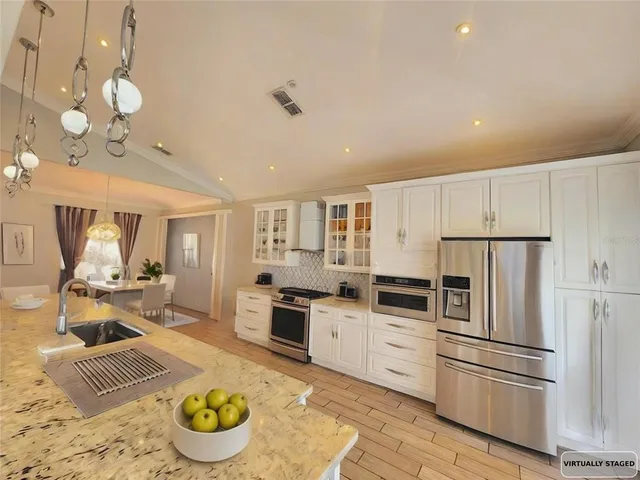 a kitchen with stainless steel appliances kitchen island granite countertop a stove a refrigerator and a refrigerator