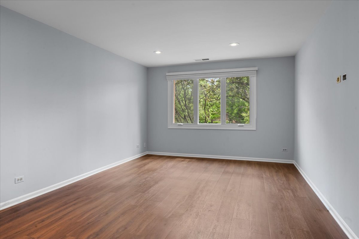 1795 Lake Cook Road, Unit 107 Highland Park, IL 60035 - Photo 13 of 26 a view of an empty room with wooden floor and a window