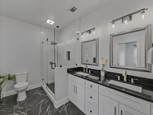 a spacious bathroom with a granite countertop sink a toilet a mirror and shower