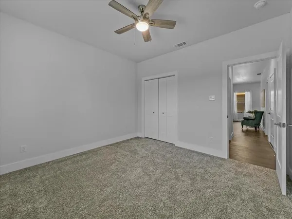 an empty room with closet and a chandelier fan