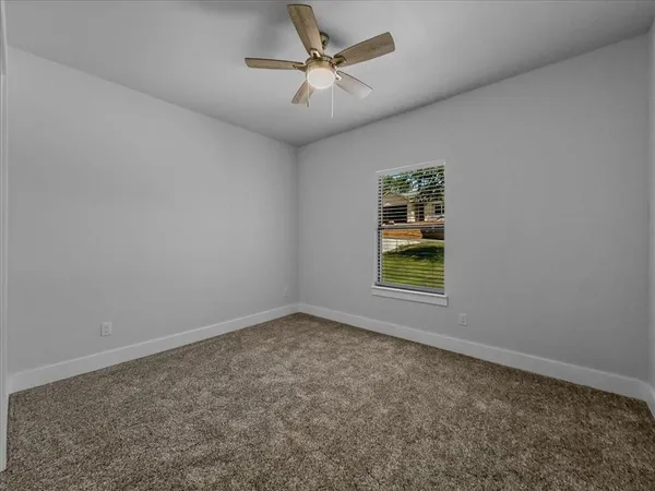 an empty room with window and ceiling fan