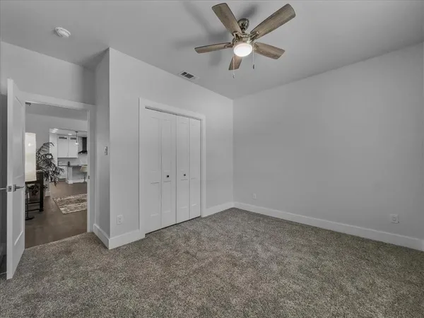 an empty room with closet and a ceiling fan