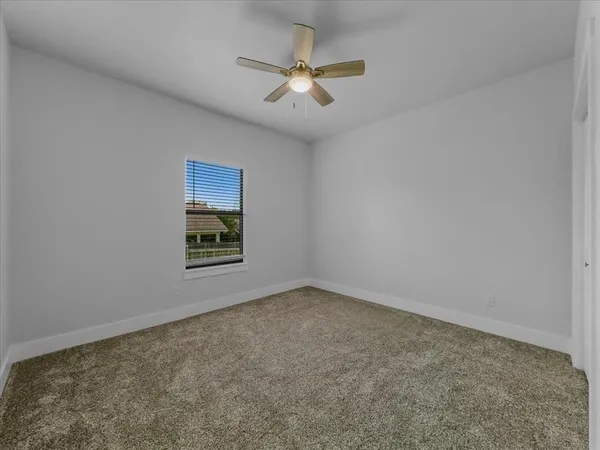 an empty room with a ceiling fan and window