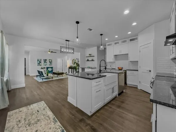 a kitchen with granite countertop a sink cabinets and wooden floor