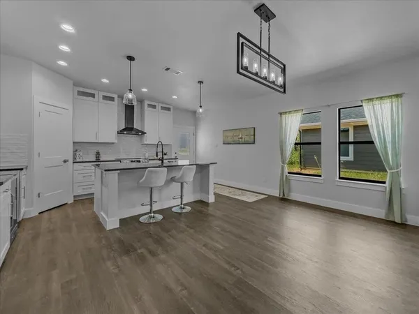 a kitchen with kitchen island stainless steel appliances a dining table chairs sink and stove