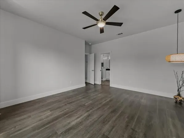 an empty room with wooden floor and a ceiling fan