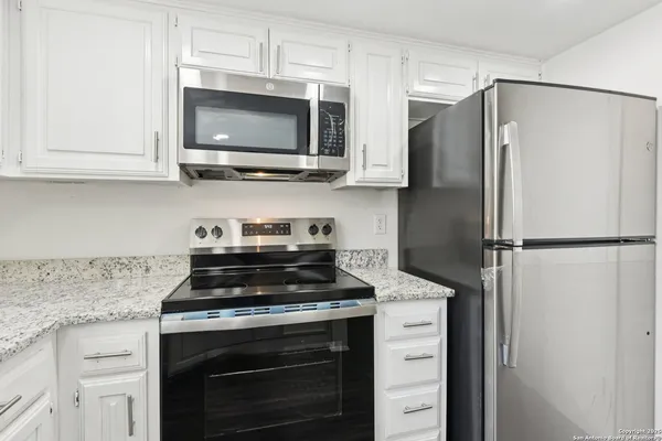 a kitchen with stainless steel appliances white cabinets and a stove a refrigerator with wooden floor