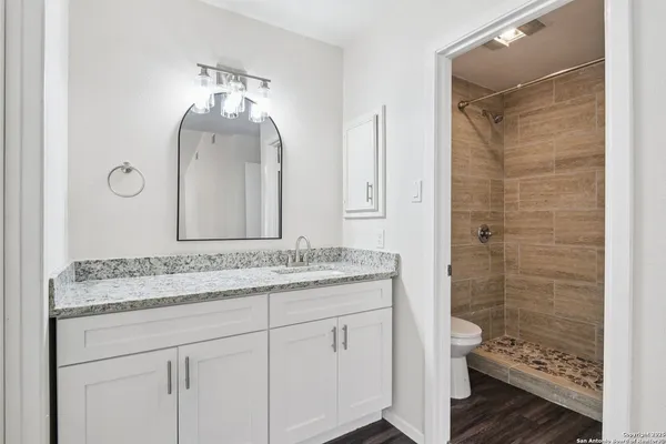 a bathroom with a granite countertop sink a toilet and a mirror