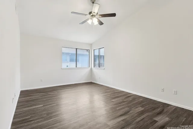 a view of an empty room with window and a chandelier fan