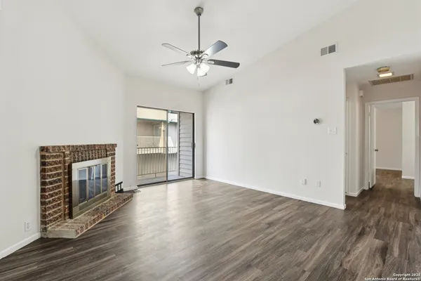 an empty room with wooden floor fireplace and windows