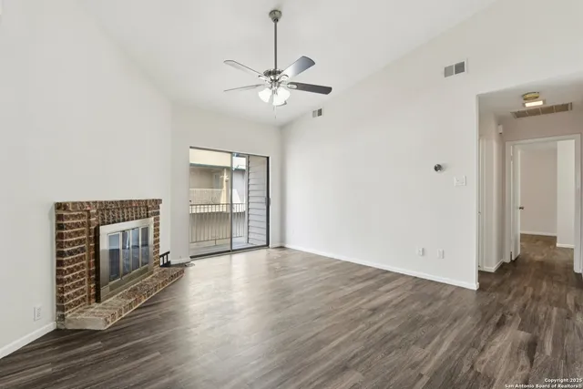 an empty room with wooden floor fireplace and windows