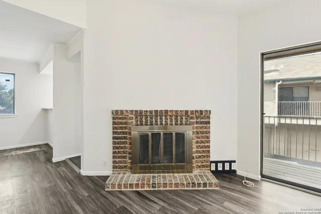 a view of a livingroom with wooden floor and a fireplace