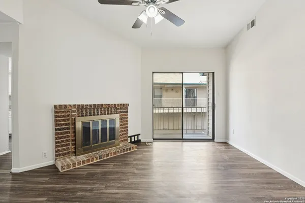 an empty room with wooden floor fireplace and windows