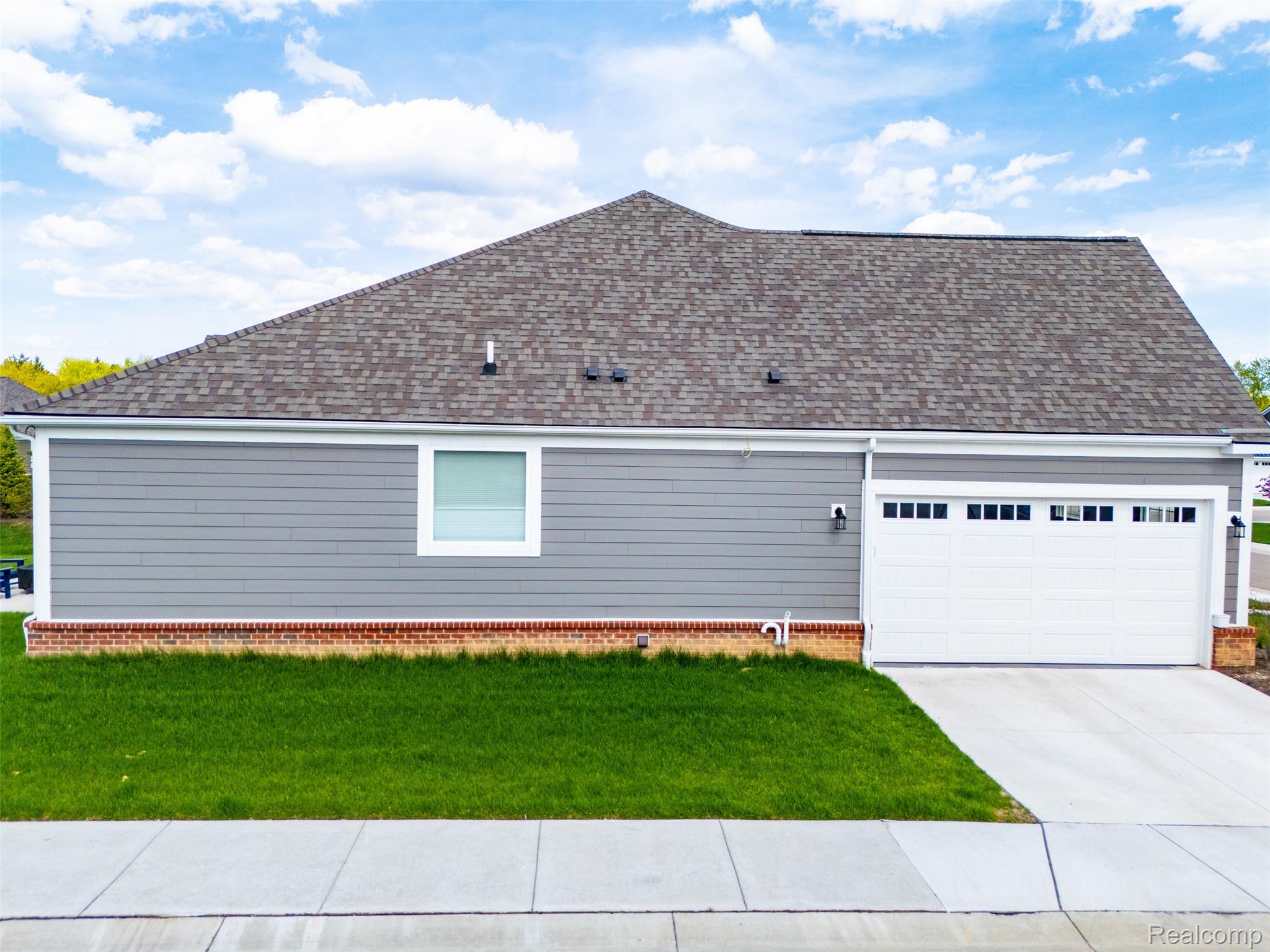 2556 Rosemond Lane Rochester, MI 48309 - Photo 54 of 64 View of side of property featuring a lawn, roof with shingles, an attached garage, and driveway