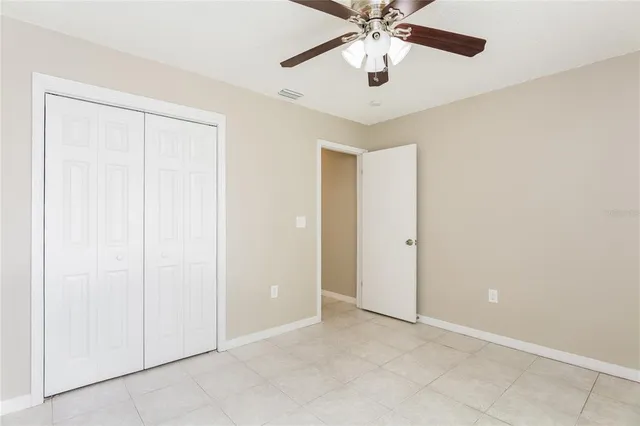 an empty room with closet and a chandelier fan