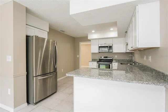 a kitchen with granite countertop a refrigerator and a sink