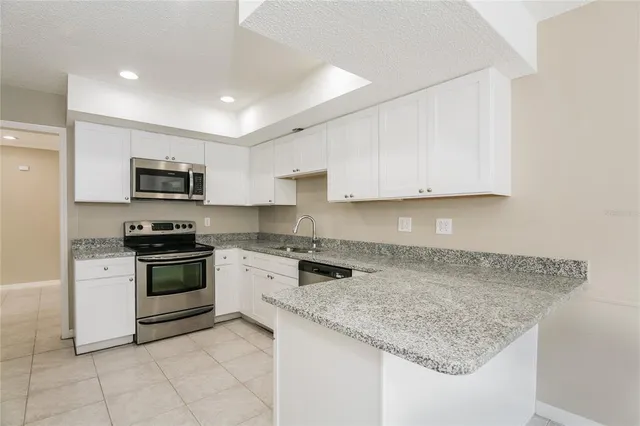 a kitchen with granite countertop a stove sink and microwave