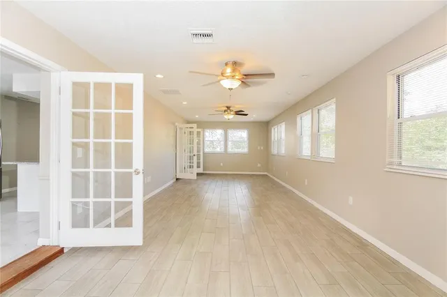 a view of an empty room with a window and wooden floor