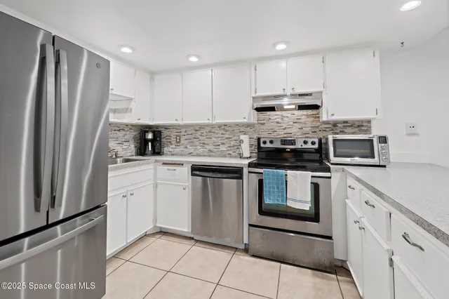 a kitchen with granite countertop a refrigerator sink and cabinets