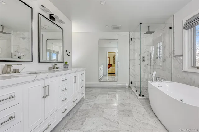 a spacious bathroom with double sink a large mirror and a bathtub