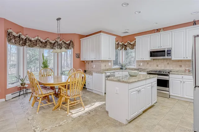 a kitchen with kitchen island granite countertop a table chairs microwave and cabinets