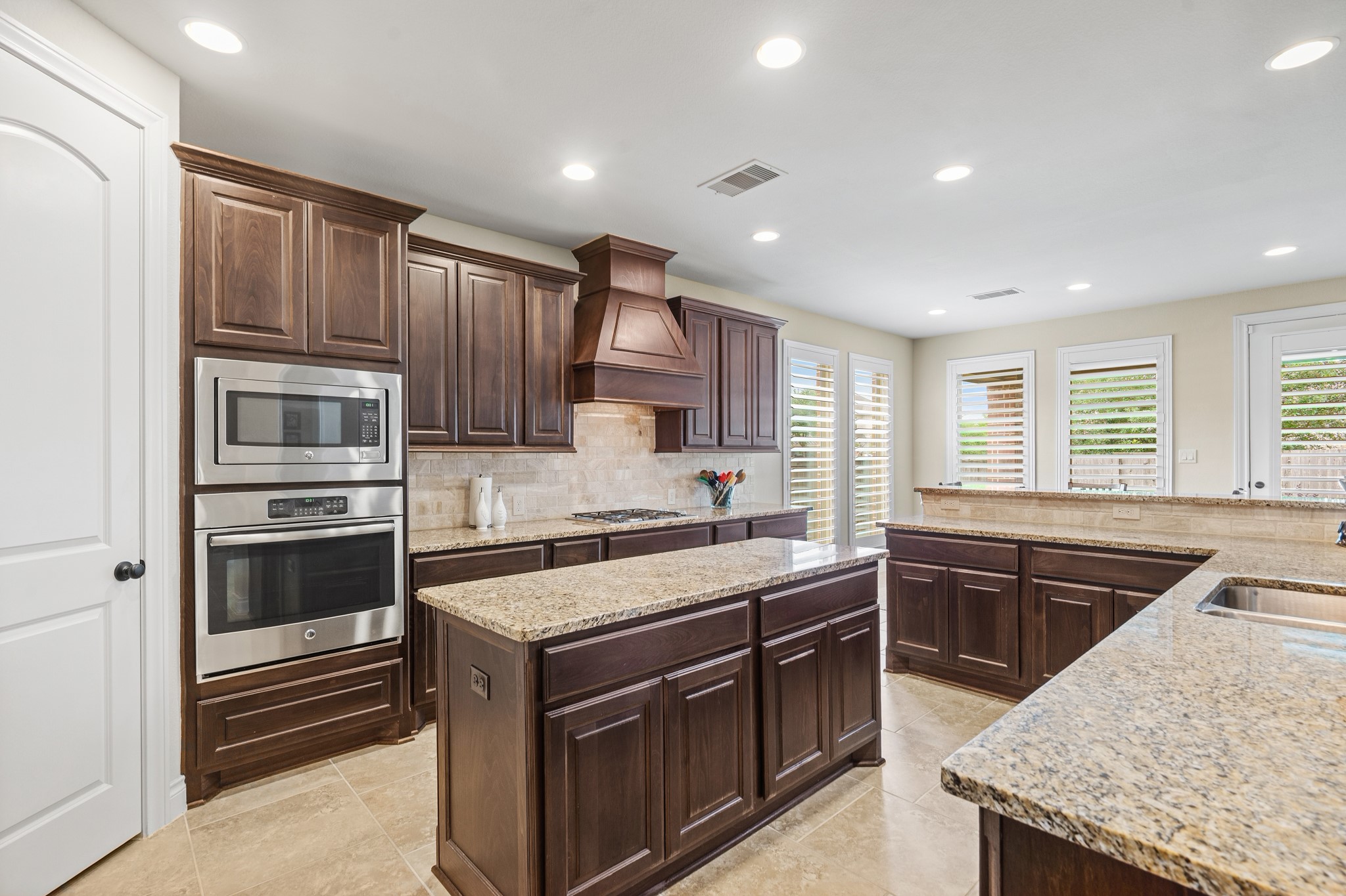 1607 Quail Ridge Drive Katy, TX 77493 - Photo 9 of 33 This stunning kitchen is designed to impress, featuring an oversized island, custom cabinetry, and sleek granite countertops that blend style with functionality. High-end stainless steel appliances, walk-in pantry, and a beautiful backsplash create a polished, modern feel. Perfectly laid out for both entertaining and everyday living, this space truly serves as the heart of the home.