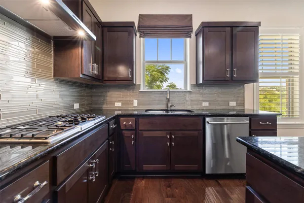 a kitchen with stainless steel appliances granite countertop a stove a sink dishwasher and cabinets with wooden floor